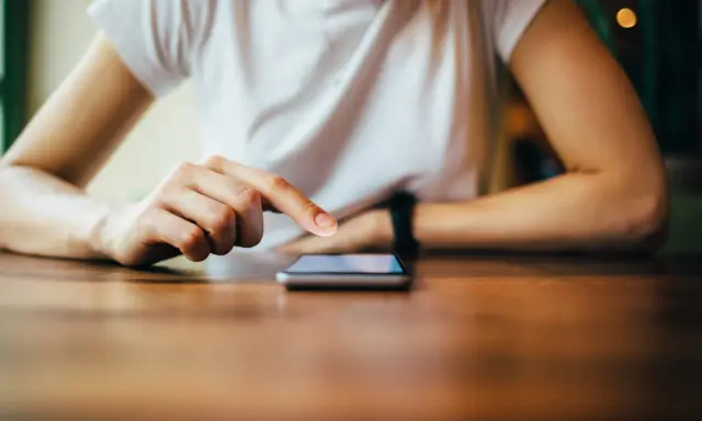 Dłoń dotyka ekranu telefonu, być może wykonując twardy reset Xiaomi.