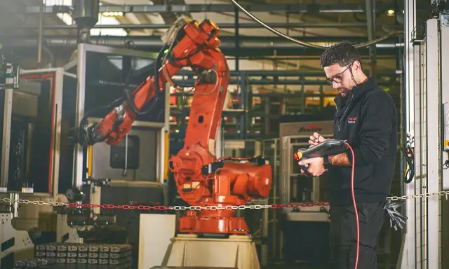 Un disegnatore meccanico opera un braccio robotico in una fabbrica. Il suo stipendio è ben meritato per la precisione richiesta.
