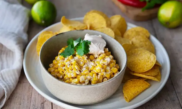 Krämig majsrätt med en klick gräddfil och koriander, serverad med tortillachips. Perfekt som tillbehör eller dipp.