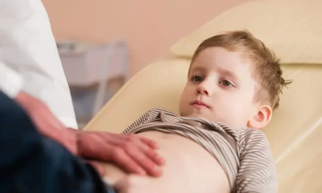 Un bambino viene visitato per sospetto neuroblastoma. Il medico gli tocca delicatamente l'addome.