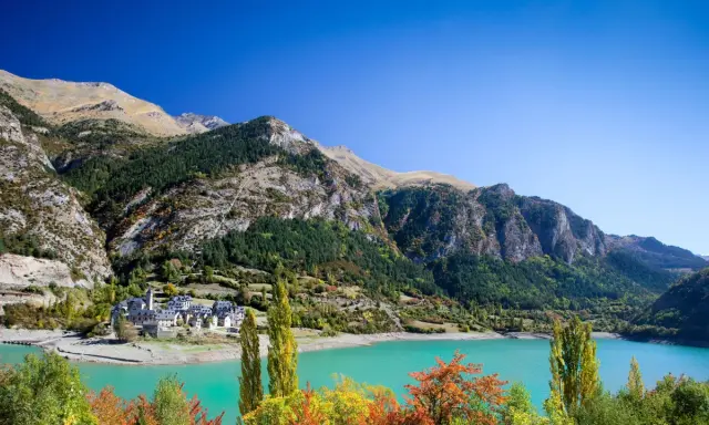 Pueblo de Lanuza, Huesca, con su embalse de aguas turquesas y montañas verdes.