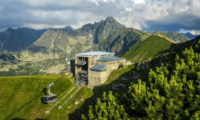 Górskie **kuźnice atrakcje** - kolejka linowa i schronisko na szczycie, otoczone majestatycznymi Tatrami.
