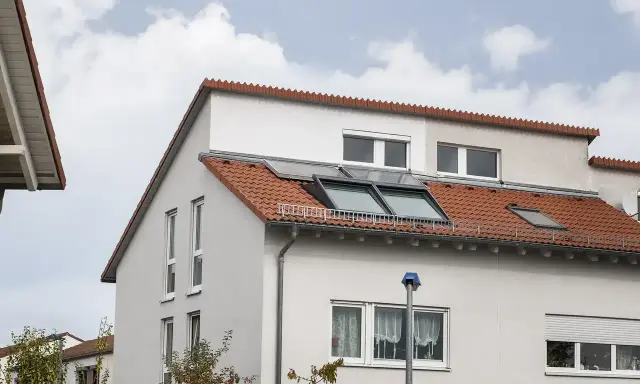 Ein Haus mit roten Ziegeln und Dachfenstern. Das Dach ist ein Pultdach, das nach einer Seite abfällt.