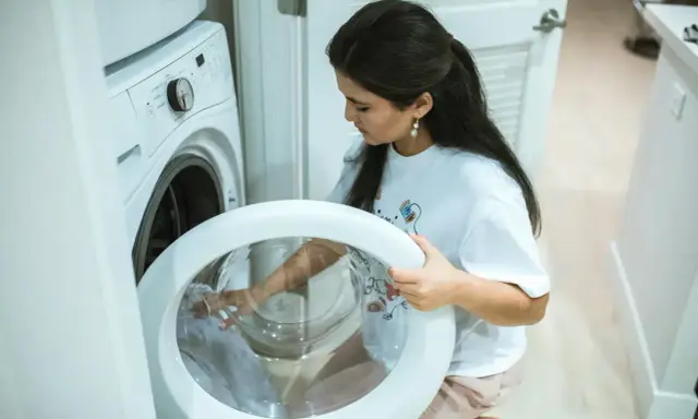 Une femme vérifie le tambour de sa machine à laver, craignant un siphon à machine à laver bouché.
