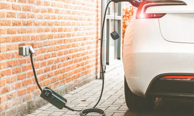 Cargando coche eléctrico a 16 amperios. El cable se conecta a la pared y al vehículo blanco.