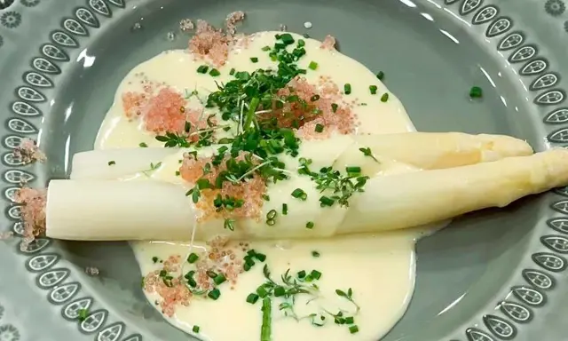 Vit sparris i en krämig sås till sparris, toppad med örter och rosa rom. En delikat rätt.