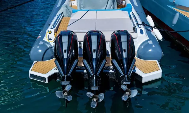 Trois puissants moteurs hors-bord noirs et rouges, prêts à propulser une chaise de luxe sur l'eau.