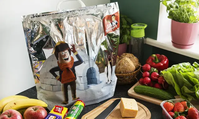 Torba termiczna z postacią z kreskówki i zimowym krajobrazem, obok świeże warzywa i owoce. Idealna, by jak przewieźć jedzenie bez lodówki.