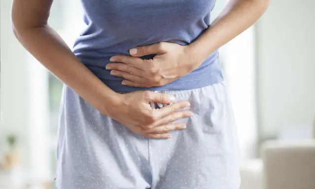 Kobieta trzyma się za brzuch, cierpiąc z powodu bólu menstruacyjnego nie do zniesienia.