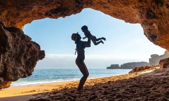Madre levanta a su bebé en una cueva en el Algarve. Un día perfecto de algarve con niños.