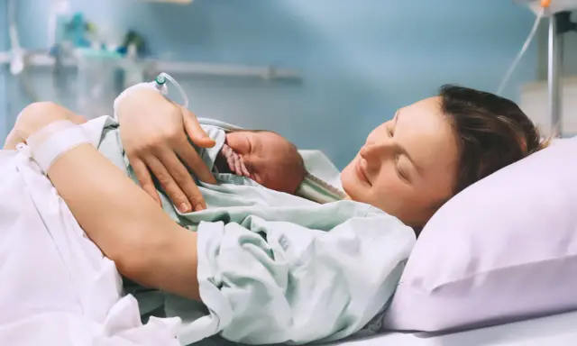 Szczęśliwa mama tuli noworodka po porodzie, czując ulgę po znieczuleniu.