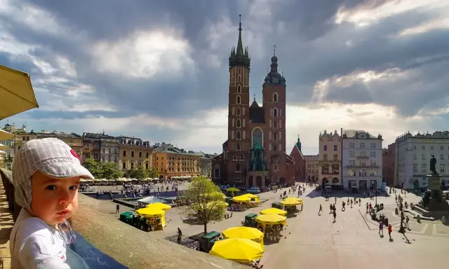 Dziecko na tle Rynku Głównego w Krakowie. To jedno z fajnych miejsc w Krakowie dla młodzieży, pełne życia i zabytków.