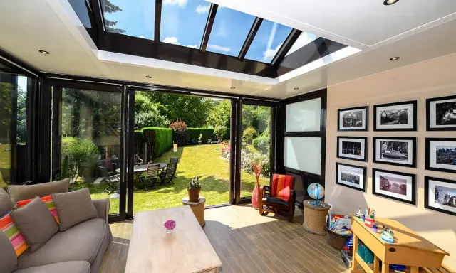 Un salon lumineux avec un canapé confortable, une table basse en bois, et une vue imprenable sur un jardin verdoyant depuis cette **veranda interieur**.