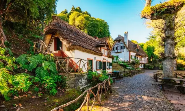 Casitas de cuento con tejados de paja, perfectas para crear viajes inolvidables para adolescentes. Un camino empedrado y vegetación exuberante.