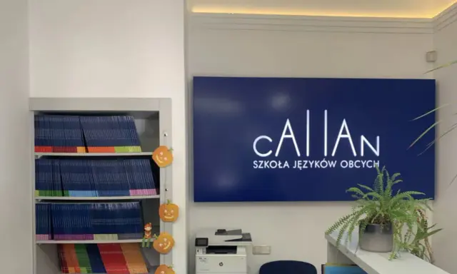 Szkoła językowa oferująca angielski metodą Callana. Na półkach książki, obok dynie. Na ścianie logo szkoły.