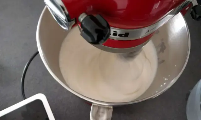 Un robot pâtissier rouge mélange une crème onctueuse, étape clé pour réussir une pâte à bombe aérienne.