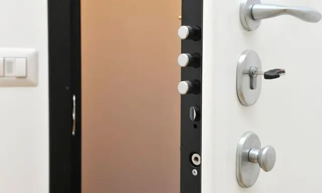 Detalle de una puerta de seguridad con varios tipos de cerraduras y un cerrojo con llave.