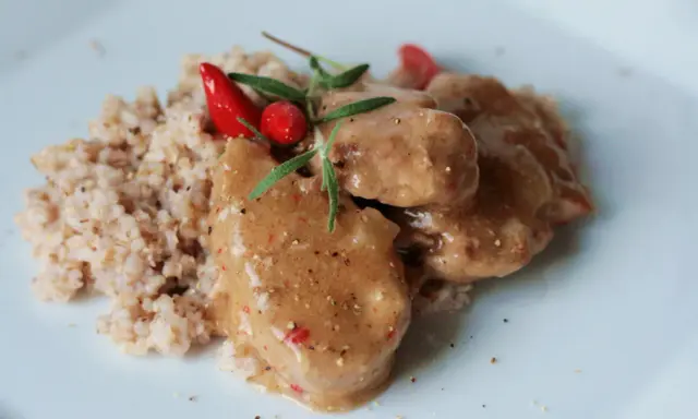 Polędwiczki wieprzowe w sosie własnym, danie Ani gotuje, podane z kaszą i ozdobione papryczką chili i rozmarynem.