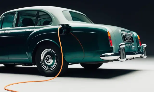 Clásico Bentley con cable de carga naranja conectado. Un ejemplo de retrofit que es la electrificación de vehículos antiguos.