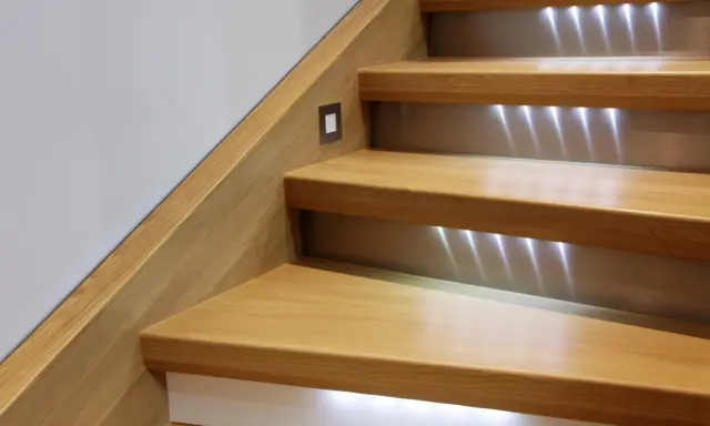 Escalier en bois rénové avec éclairage LED discret. Un design moderne pour un escalier chaleureux.