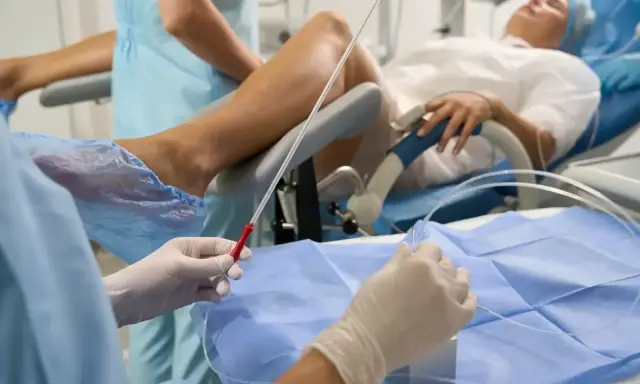 Person w rękawiczkach przygotowuje się do procedury, która może pomóc w oddawaniu moczu po wyjęciu cewnika. Pacjentka leży na fotelu ginekologicznym.