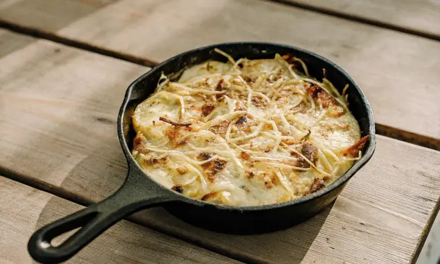 Gratin dauphinois, une spécialité Auvergne, doré et gratiné dans sa poêle en fonte sur une table en bois.