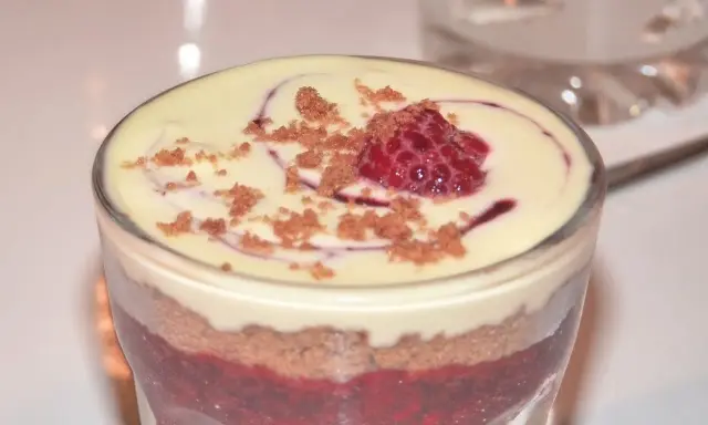 Verrine speculoos framboise : couches de biscuits émiettés, compotée de framboises et crème onctueuse, surmontée d'une framboise fraîche et miettes de spéculoos.