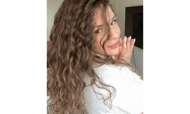 Une femme aux magnifiques cheveux bouclés, un sourire doux et des mains jointes. Elle est radieuse, ses boucles sont parfaites, sans aucun souci.