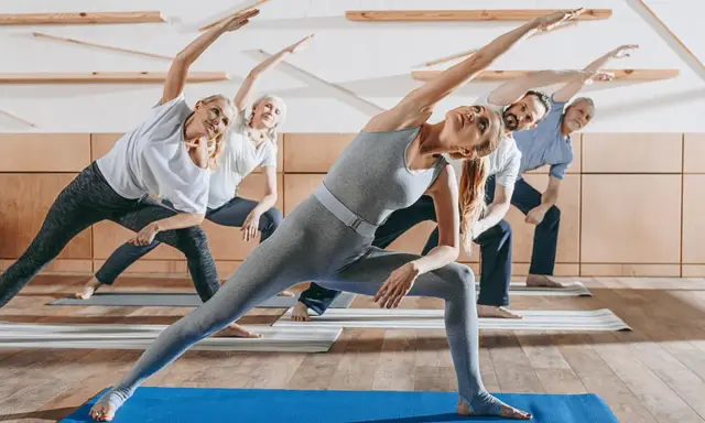 Menschen unterschiedlichen Alters üben Yoga. Sanfte Bewegungen wie diese sind ideal für Gymnastik bei Osteoporose, um Kraft und Gleichgewicht zu fördern.
