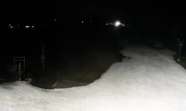 Nocne widoki z olczański wierch kamery. Ośnieżony stok i wyciąg narciarski w ciemności.