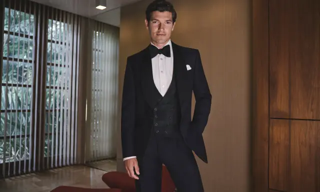 A man in a tuxedo, embodying the perfect gala dinner dress code male attire, stands confidently.