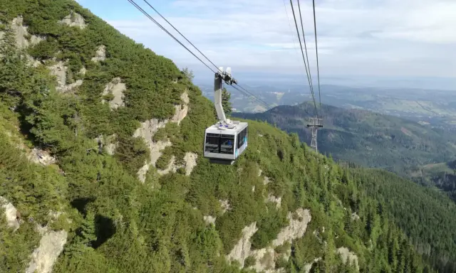 Kolejka linowa na Kasprowy Wierch wjeżdża na zielone, skaliste zbocze górskie.