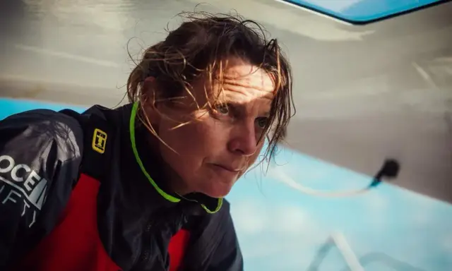 Anne Claire Le Berre, concentrée, le regard intense, le visage marqué par le soleil et le vent, sur un bateau.