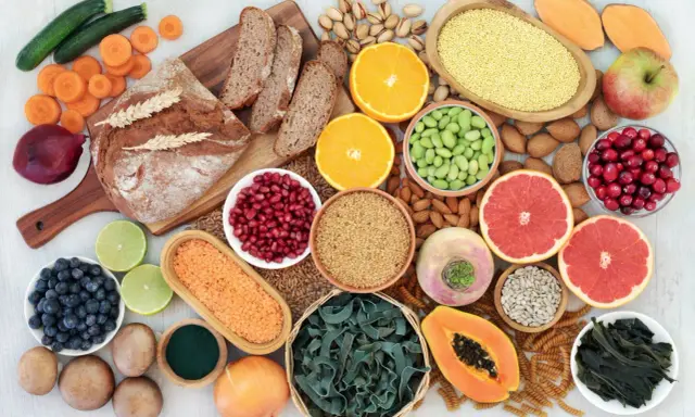 Vielfalt an ballaststoffe produkten: Vollkornbrot, Linsen, Beeren, Nüsse, Obst und Gemüse für eine gesunde Ernährung.
