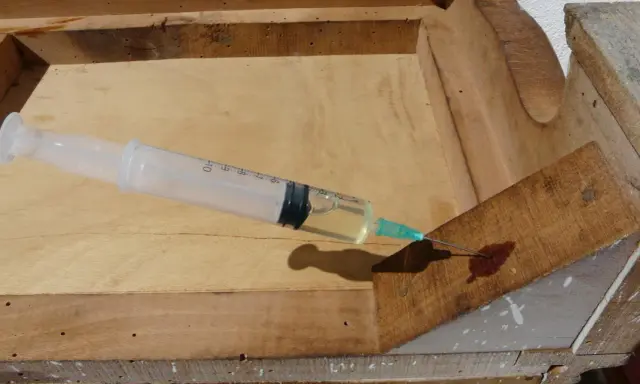 Jeringa inyectando líquido para eliminar carcoma en madera vieja.