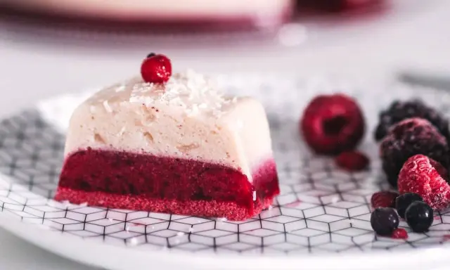 Deliciosa gelatina con agar agar, con capa roja de frutos rojos y capa superior cremosa, decorada con coco rallado y una baya.
