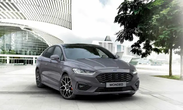 Ford Mondeo gris aparcado frente a un edificio moderno. Las medidas del Ford Mondeo son ideales para la ciudad.