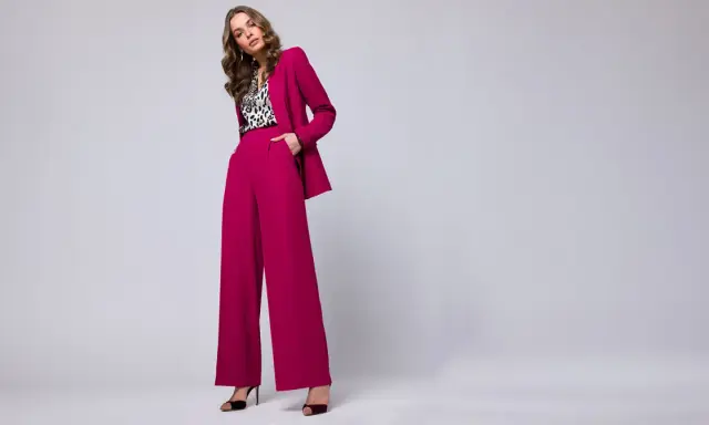 Elegancka stylizacja na chrzciny ze spodniami: fuksjowy garnitur z szerokimi nogawkami i bluzka w panterkę.
