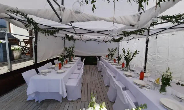 Elegancka komunia w namiocie. Białe obrusy, kwiaty i szklane lampiony tworzą uroczystą atmosferę.
