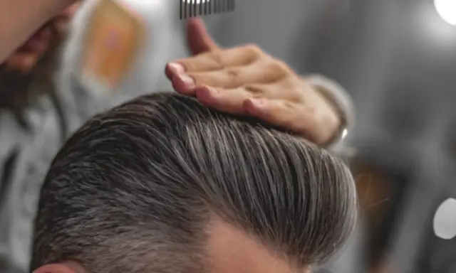 Stylista układa włosy, pokazując, jak mieć gęste włosy chłopak.