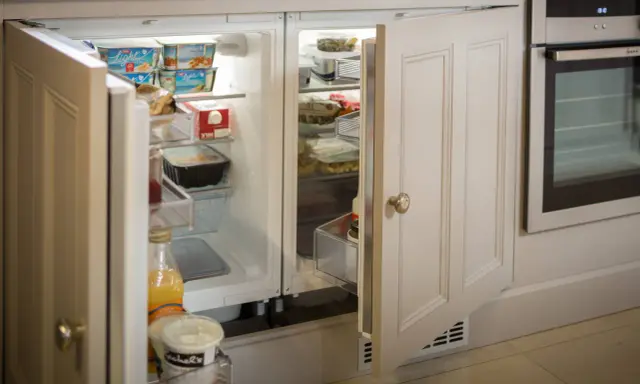 Un frigorifero integrato, quasi invisibile, con ante in legno che si fondono con l'arredamento, perfetto per nascondere il frigorifero in soggiorno.