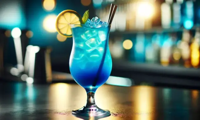 Orzeźwiający blue lagoon drink z lodem, plasterkiem cytryny i miętą, podany w eleganckim kieliszku na tle rozmytego baru.