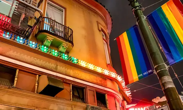 Rainbow flags fly proudly in the gayest city in America, illuminating a building with colorful lights.