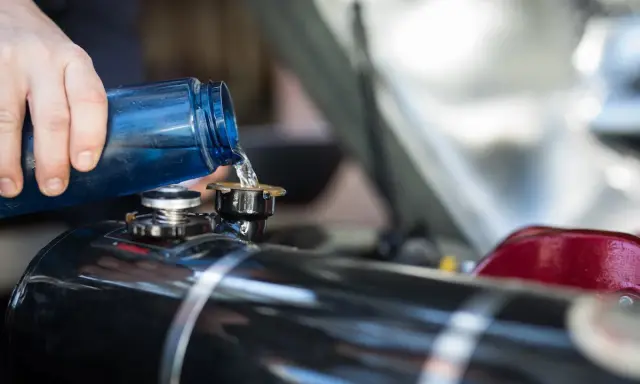 Maintenir le moteur 4 temps en bon état : on verse du liquide de refroidissement bleu dans le réservoir.