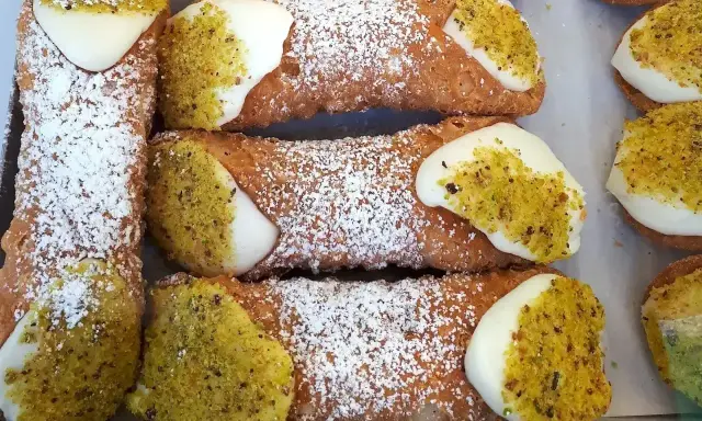 Chrupiące rurki z kremem, posypane cukrem pudrem i pistacjami, kuszą swoim wyglądem.