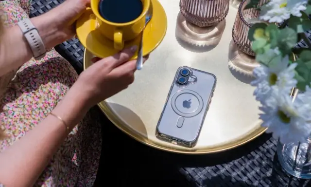 Eleganckie etui przezroczyste z wzorami na telefon, leżące obok żółtej filiżanki kawy i białych kwiatów.