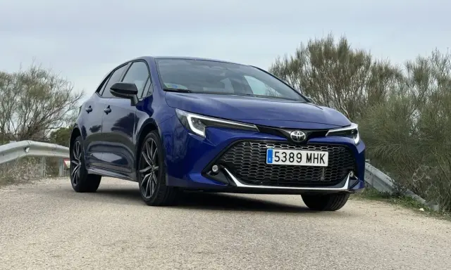 Toyota Corolla blu parcheggiata su strada sterrata, con vegetazione sullo sfondo. Un'auto che offre diverse motorizzazioni.