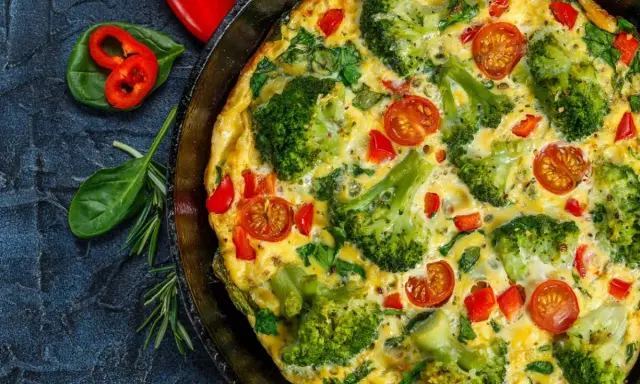 Pyszny omlet na słono z brokułami, pomidorkami i papryką, podany w patelni.