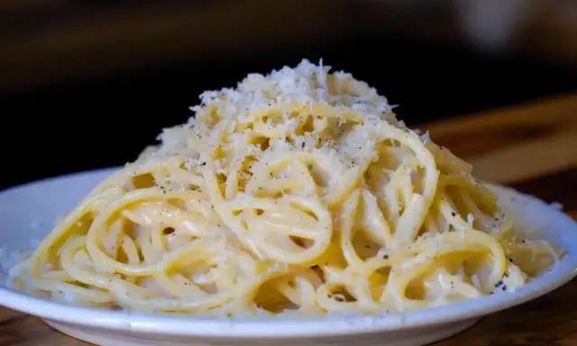 Pyszne cacio e pepe, czyli spaghetti z serem i pieprzem, posypane startym parmezanem.