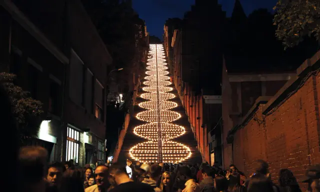 Beleuchtete Treppe in Büren bei Nacht, umgeben von Menschen und Gebäuden.
